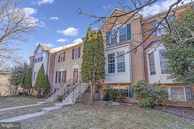 townhome / multi-family property with brick siding and a front lawn