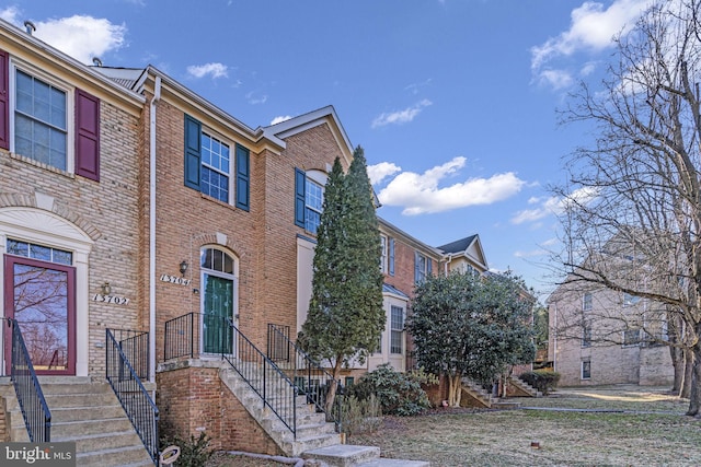 view of property featuring stairs and brick siding