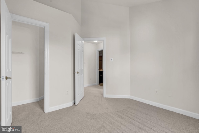 unfurnished bedroom featuring light carpet and baseboards