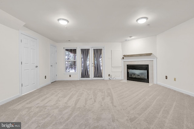 unfurnished living room with light carpet, baseboards, and a tiled fireplace