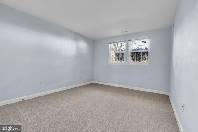 carpeted spare room with visible vents and baseboards