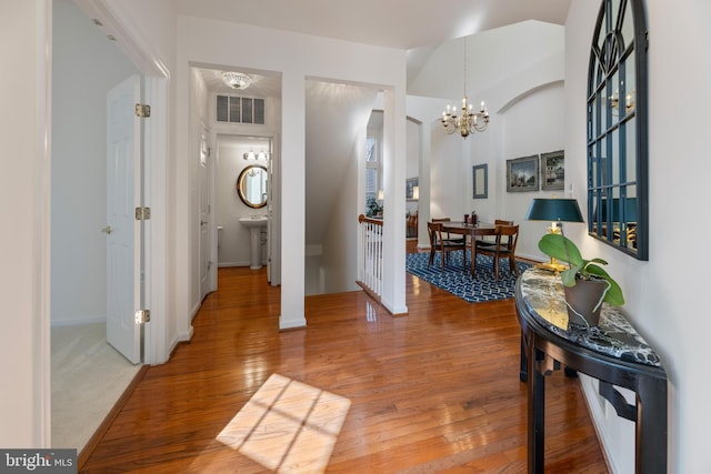 entrance foyer featuring baseboards, visible vents, an inviting chandelier, and wood finished floors