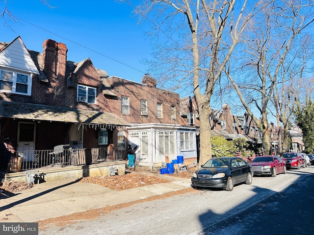 view of property with a residential view, a chimney, and brick siding