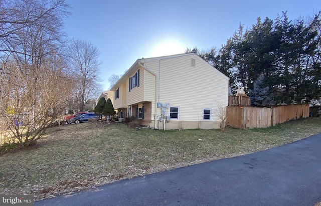 view of property exterior with a lawn and fence