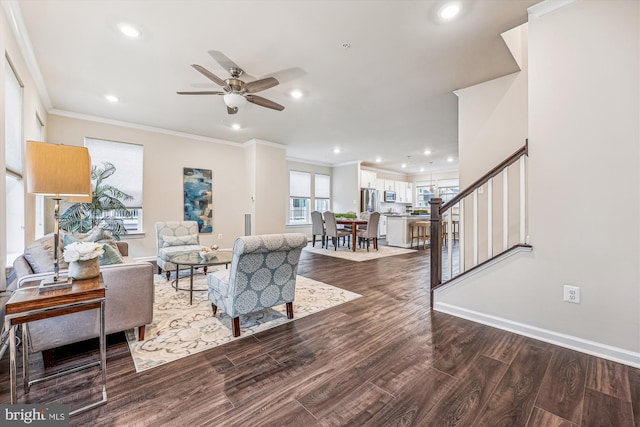 living room featuring stairs, baseboards, wood finished floors, and crown molding