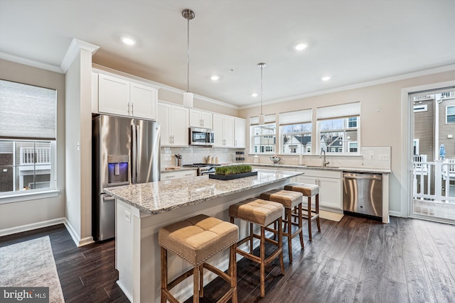 kitchen with stainless steel appliances, a kitchen island, white cabinetry, decorative backsplash, and crown molding