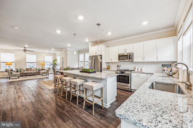 kitchen featuring light stone counters, stainless steel appliances, a breakfast bar, a kitchen island, and a sink