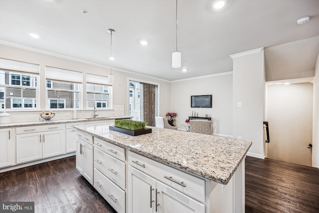 kitchen with ornamental molding, dark wood-style flooring, a kitchen island, and white cabinetry