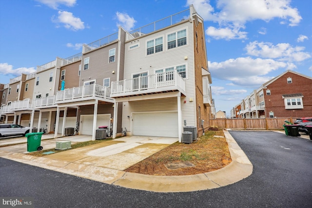 back of property featuring driveway, central AC unit, and a residential view