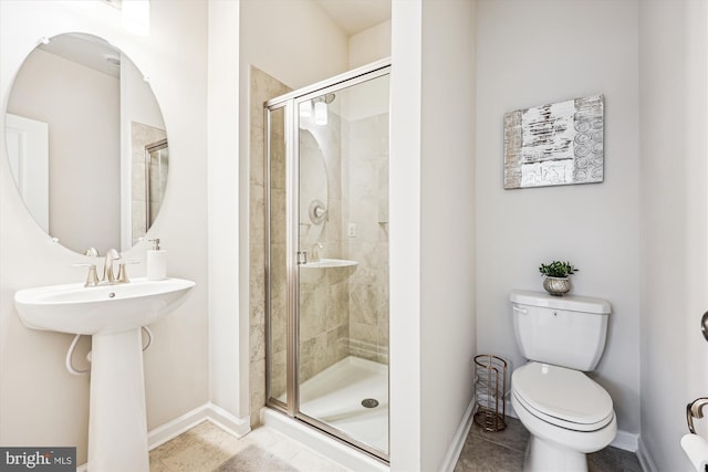 bathroom featuring a stall shower, baseboards, toilet, and tile patterned floors