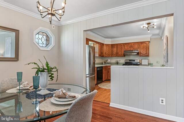 dining room with an inviting chandelier, wood finished floors, and ornamental molding