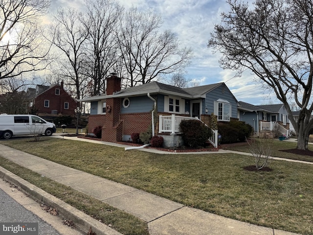 view of front of house featuring a front yard, brick siding, and a chimney