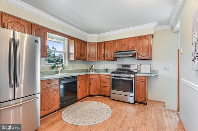 kitchen with ornamental molding, under cabinet range hood, light wood-style floors, appliances with stainless steel finishes, and light countertops