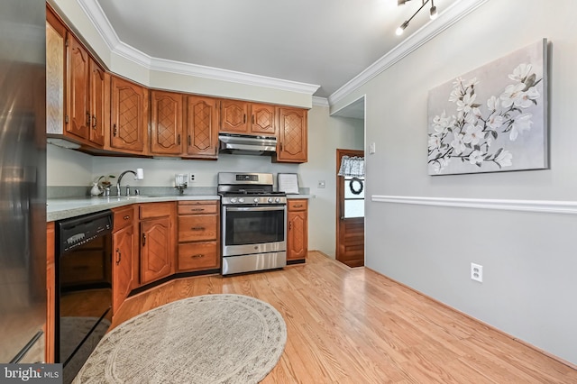 kitchen featuring ornamental molding, under cabinet range hood, a sink, stainless steel appliances, and light wood finished floors