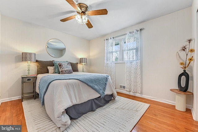 bedroom featuring visible vents, a ceiling fan, baseboards, and wood finished floors