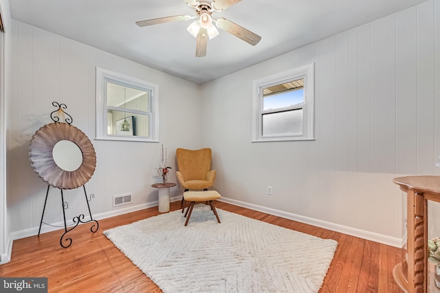 sitting room featuring baseboards, wood finished floors, visible vents, and ceiling fan