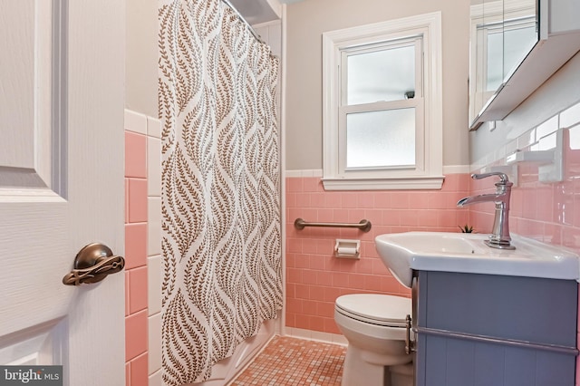 bathroom with vanity, tile patterned flooring, wainscoting, tile walls, and toilet