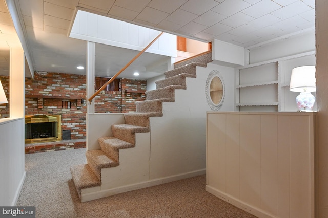 stairway with baseboards, carpet, and a brick fireplace