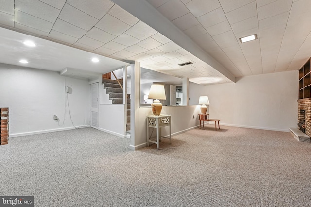 finished basement with visible vents, baseboards, stairs, and carpet