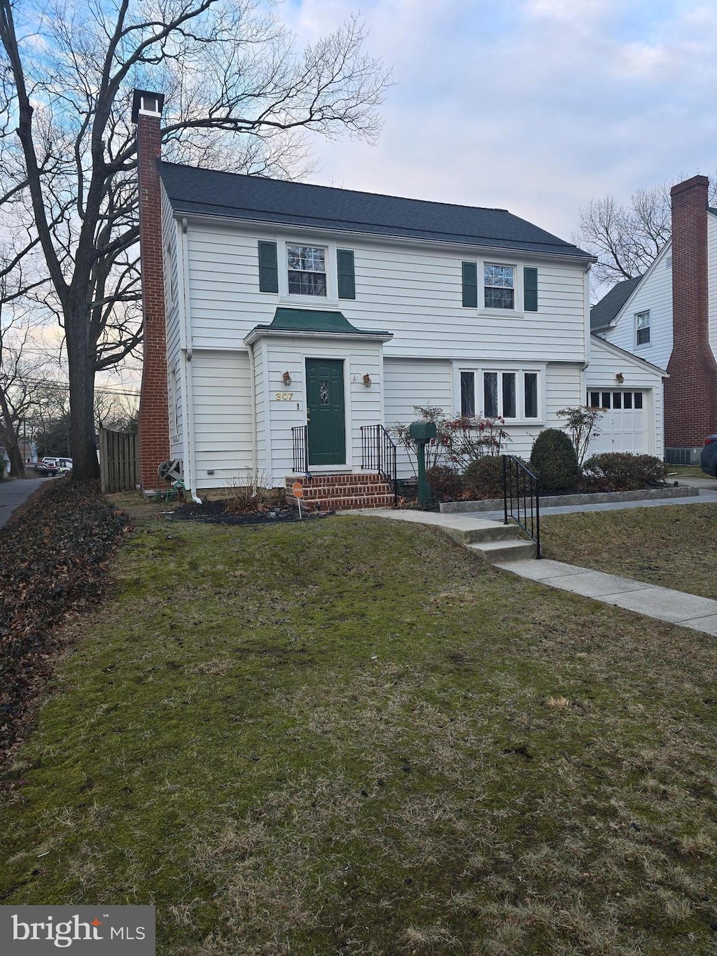 view of front facade with a garage, a chimney, and a front lawn