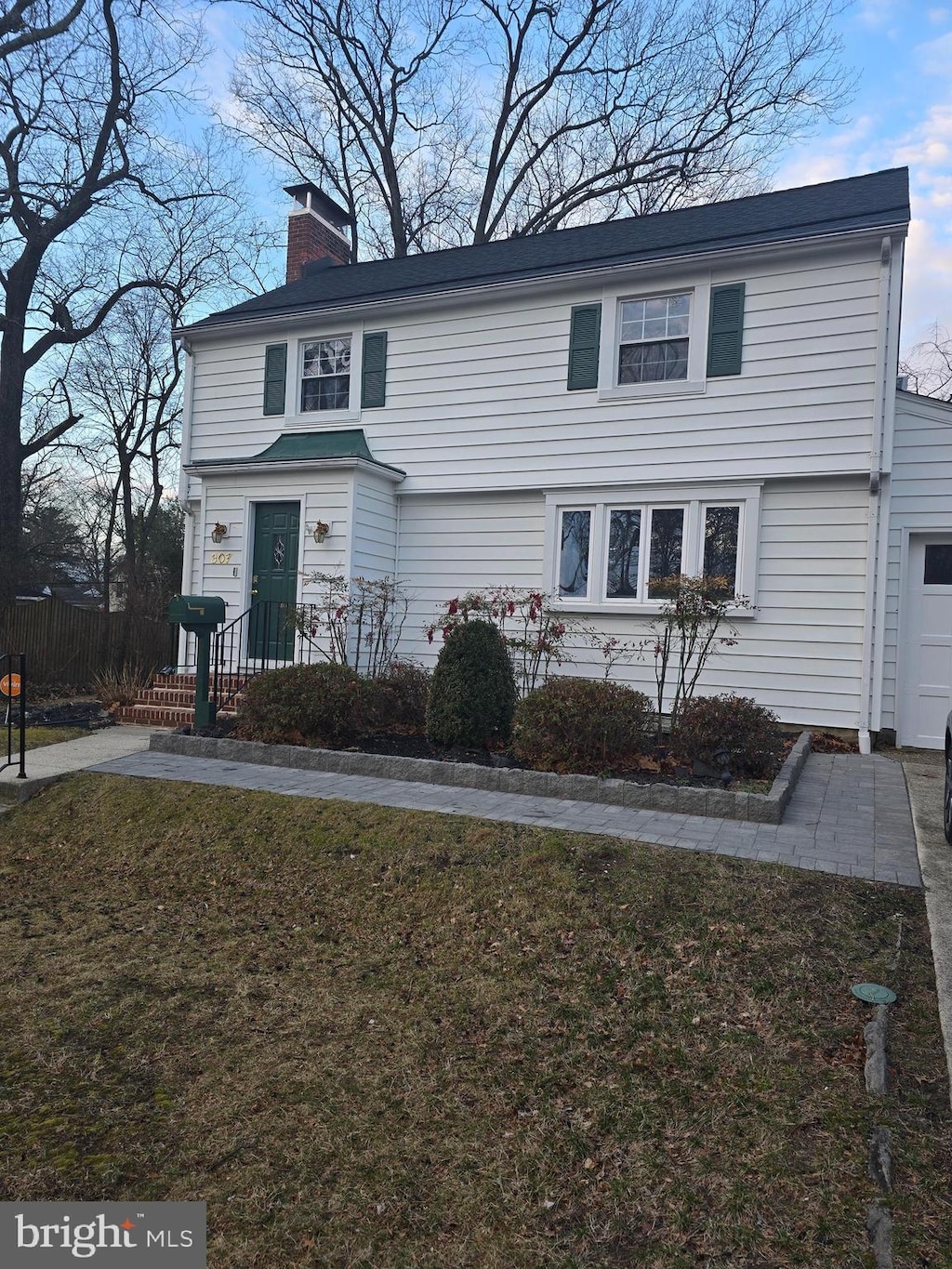 view of front facade featuring a garage, a chimney, and a front lawn