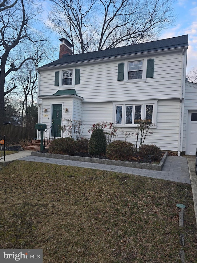 view of front facade featuring a garage, a chimney, and a front lawn