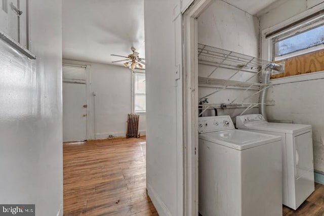 clothes washing area with radiator, a healthy amount of sunlight, independent washer and dryer, and wood finished floors