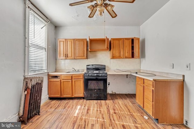 kitchen with open shelves, wall chimney range hood, a sink, and black gas range oven