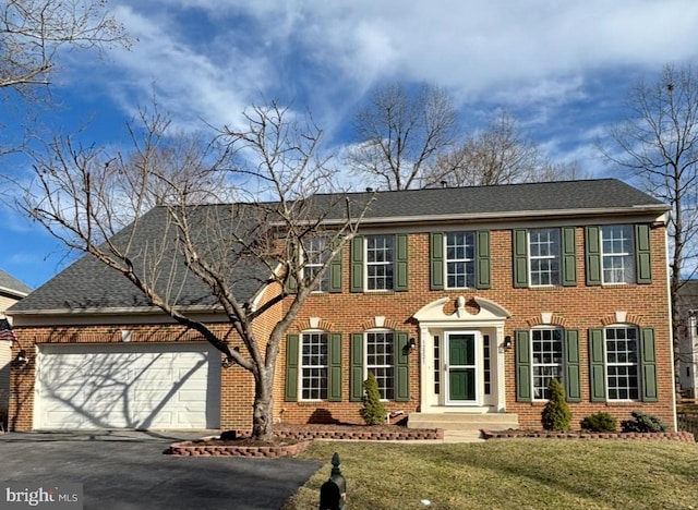 view of front of home with driveway, a front lawn, an attached garage, and brick siding