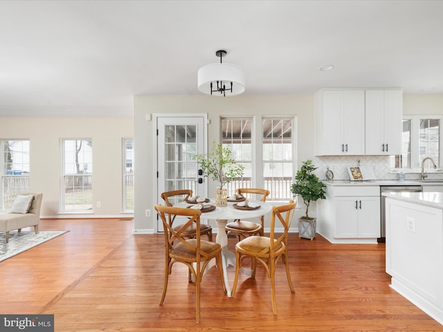 dining space with light wood-type flooring, baseboards, and a wealth of natural light