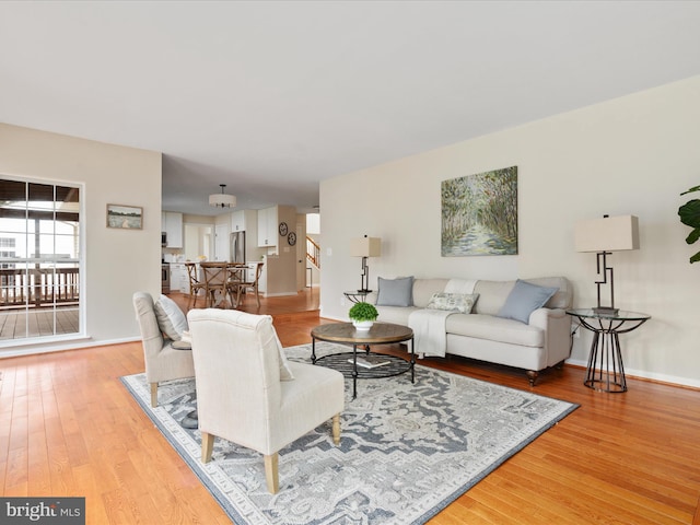 living area with stairway, light wood-style flooring, and baseboards