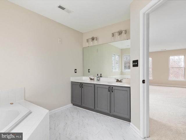 full bathroom featuring marble finish floor, double vanity, visible vents, a sink, and a bath