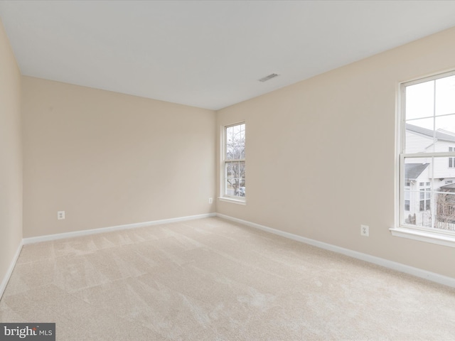 spare room featuring baseboards, visible vents, and light colored carpet