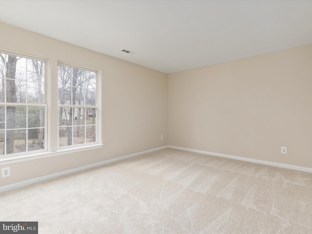 empty room featuring light colored carpet, visible vents, and baseboards