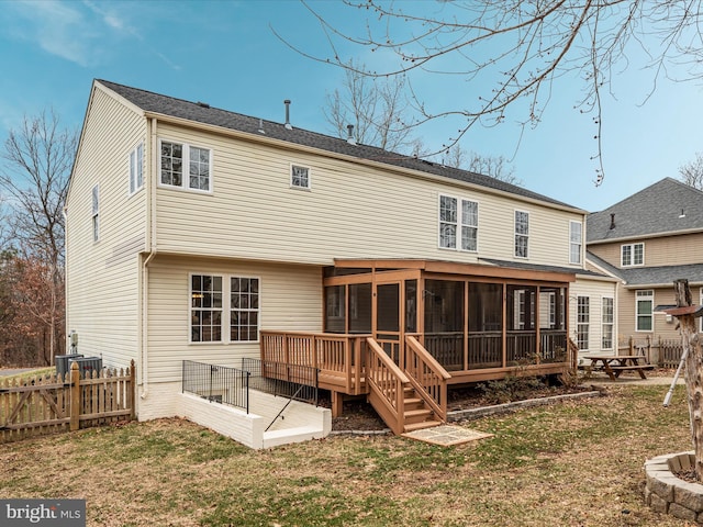 rear view of property featuring a yard, a sunroom, and fence