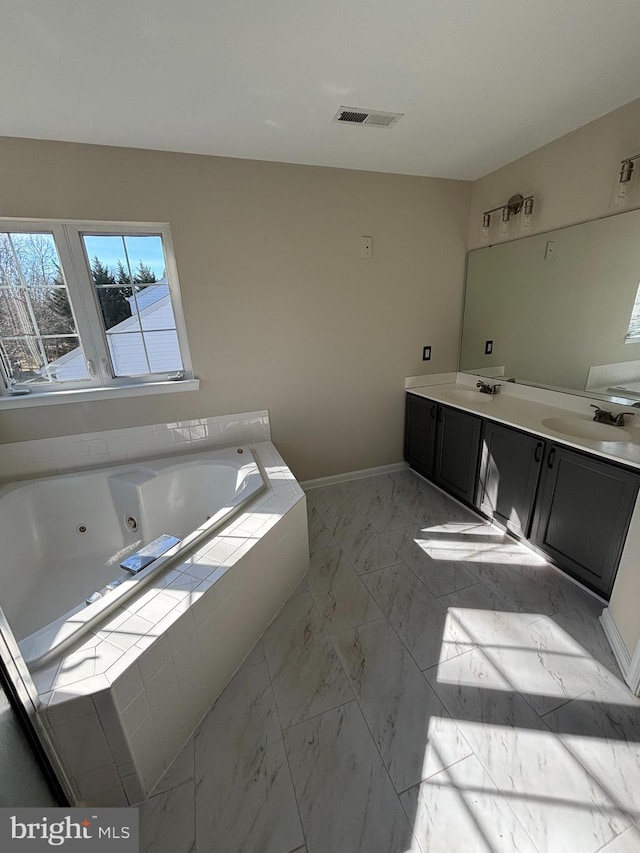 bathroom with marble finish floor, visible vents, a sink, a whirlpool tub, and baseboards