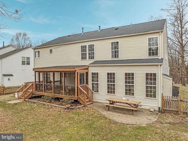 rear view of house with fence, a yard, roof with shingles, a wooden deck, and a patio area