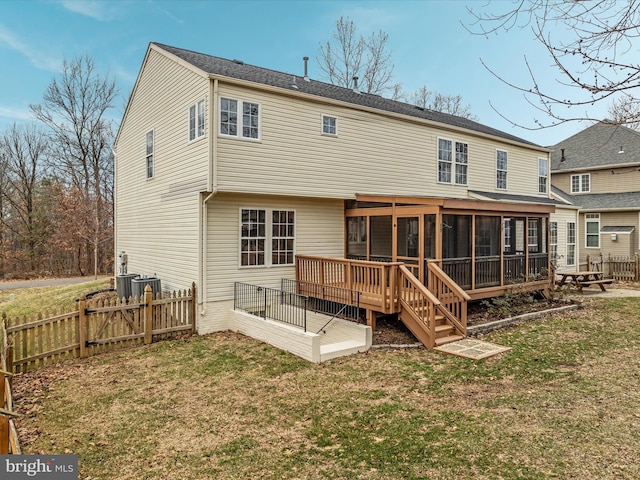 back of property featuring a sunroom, fence, a deck, and a lawn