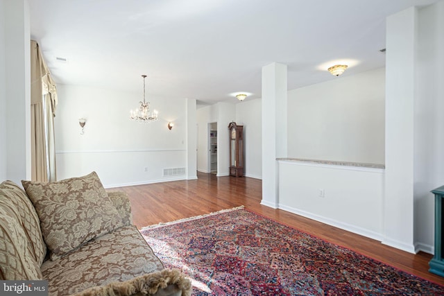 living room with a notable chandelier, dark wood-style flooring, visible vents, and baseboards