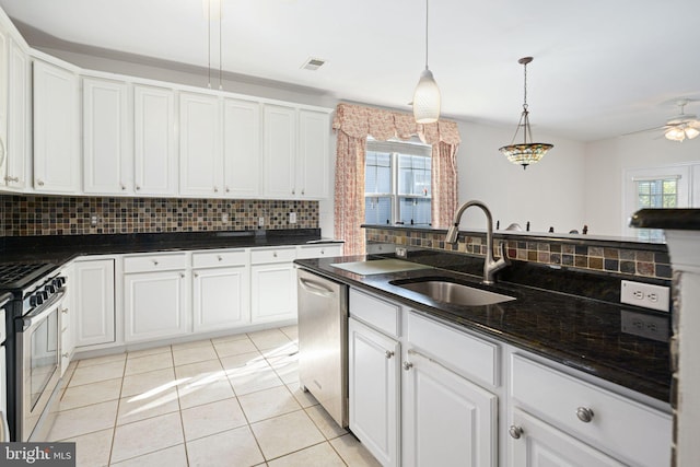 kitchen with hanging light fixtures, backsplash, appliances with stainless steel finishes, white cabinets, and a sink