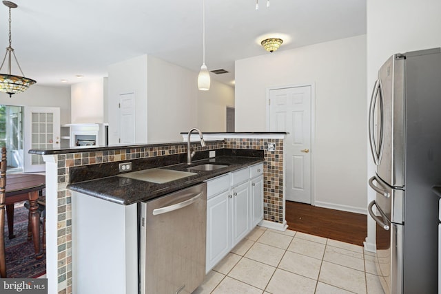 kitchen with decorative light fixtures, appliances with stainless steel finishes, white cabinetry, a sink, and light tile patterned flooring