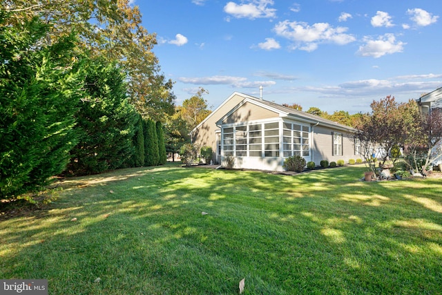 rear view of property featuring a sunroom and a lawn