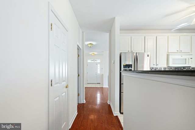 hallway featuring dark wood finished floors and baseboards