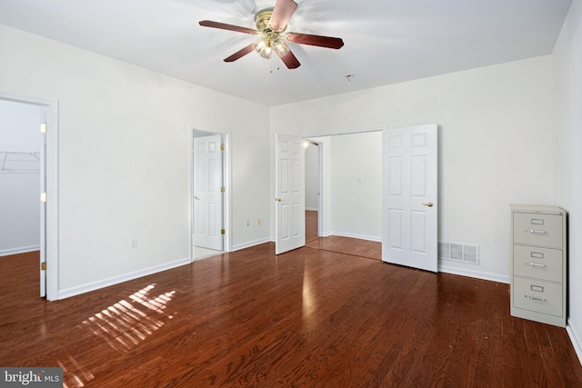 unfurnished bedroom with dark wood-type flooring, visible vents, a spacious closet, and baseboards