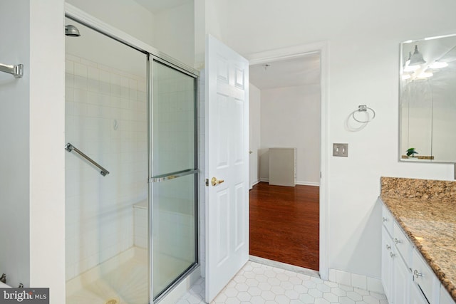 full bathroom with tile patterned flooring, a shower stall, vanity, and baseboards