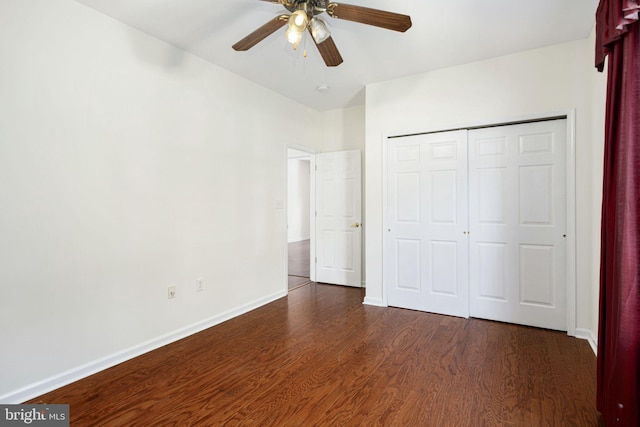 unfurnished bedroom featuring a closet, dark wood finished floors, a ceiling fan, and baseboards