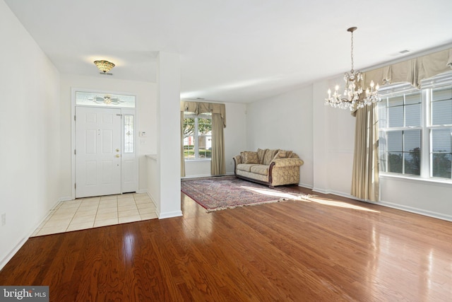 entrance foyer featuring light wood-type flooring, baseboards, visible vents, and a notable chandelier