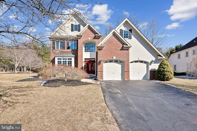 view of front of home featuring driveway, stucco siding, a garage, and brick siding