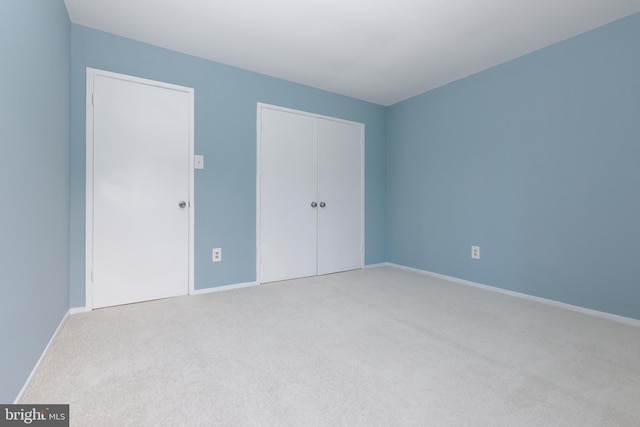 unfurnished bedroom featuring carpet floors, baseboards, and a closet