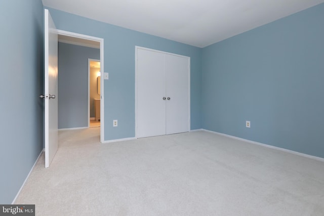 unfurnished bedroom with baseboards, a closet, and light colored carpet